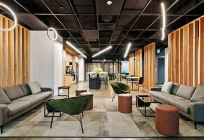 Modern lounge area with grey sofas, green armchairs, and timber wall accents.