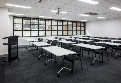 Large classroom-style training room with rows of white desks and black chairs.