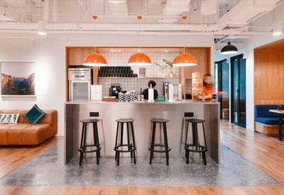 Stylish kitchen bar area with black stools, copper pendant lights, and a leather sofa nearby.