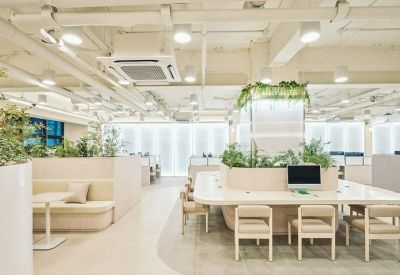 Open plan workspace with long white desks, integrated planters, and cushioned bench seating.