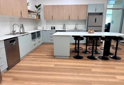 Modern communal kitchen and breakout area with a large island bench and breakfast bar stools.