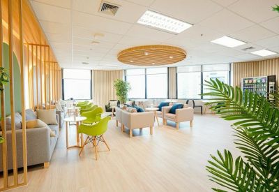Spacious communal lounge featuring vibrant green chairs, comfortable sofas, and natural light.