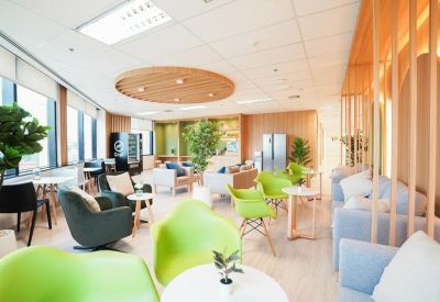 Vibrant breakroom area with lime green chairs, potted plants, and light wood flooring.