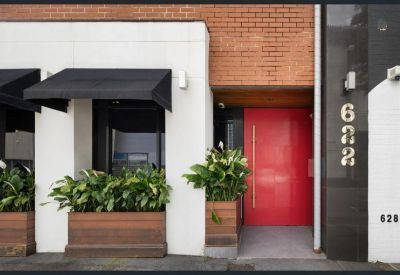 Close-up of building entrance featuring a bright red door and gold street numbering.