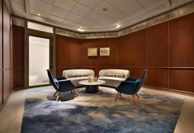 Intimate waiting area with plush velvet armchairs and a patterned rug against dark wood walls.
