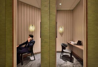 A man on a phone call inside a private acoustic phone booth with fluted walls.