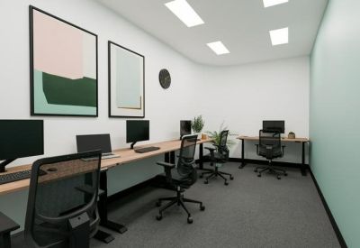 Quiet internal office with three workstations, grey carpet, and framed wall art.