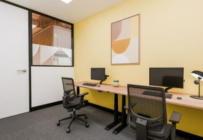 Private two-person office suite featuring a bright yellow accent wall and abstract artwork.