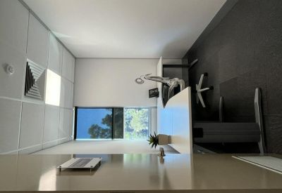 Bright workspace featuring a sleek white desk and a large window overlooking trees.