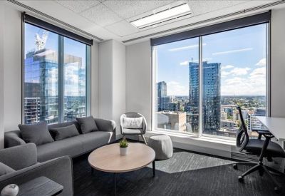 Bright breakout lounge with grey sofas and a view of the city skyline.