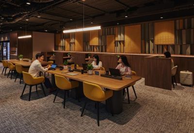Coworking space with long wooden tables and warm yellow seating.