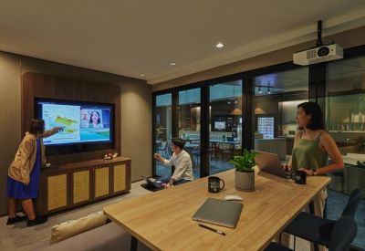 Modern meeting room equipped with a large screen and wood accents.