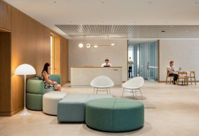 Spacious reception area with a white front desk, curved green seating, and large windows.
