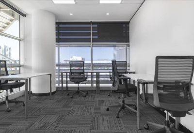 Spacious open-plan office with desks and chairs by large windows.