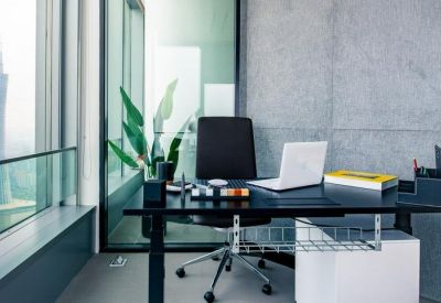 Private window office with a black desk, laptop, and panoramic views of the city skyline.