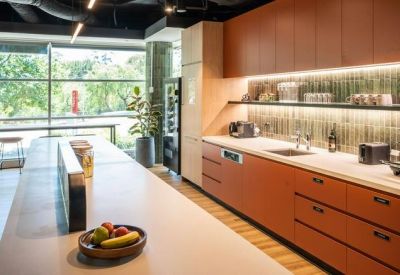 Modern kitchen and break area with terracotta cabinetry and marble countertops.
