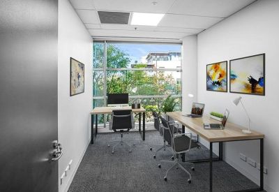 Private internal three-person office suite with light wood desks and abstract wall art.