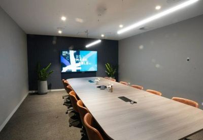 Professional meeting room featuring a long wooden table and integrated video conferencing screen.