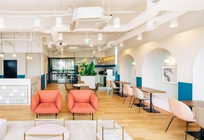 Modern reception and breakout space with peach-colored armchairs and light wood flooring.
