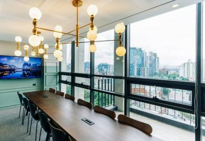 Large meeting room with a long wooden table, gold statement chandelier, and city views through floor-to-ceiling windows.