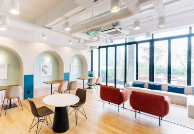Spacious lounge with arched wall alcoves, red armchairs, and a white sofa by large windows.