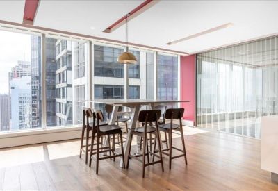 Communal breakout area with high tables, wooden floors, and city views.