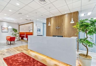 Bright reception area featuring a clean white front desk, wood-slat feature wall, and indoor greenery.