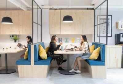 Cozy communal breakout area with blue upholstered booths and yellow throw pillows.