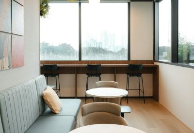 Bright communal break area with cafe-style seating, plants, and large windows.