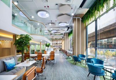 Open-plan coworking space with ergonomic chairs, blue velvet armchairs, and greenery.