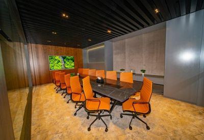 Professional boardroom with a long dark table and bright orange chairs.