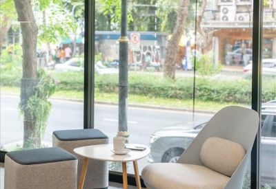 Lounge area featuring stylish armchairs and small coffee tables by a window.