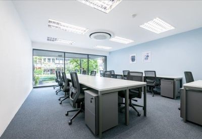Spacious open-plan workspace with multiple desks and floor-to-ceiling windows.