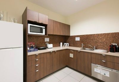Communal kitchen with wooden cabinets and a microwave.