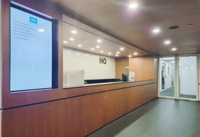 Professional reception desk with wood paneling and a digital display screen.