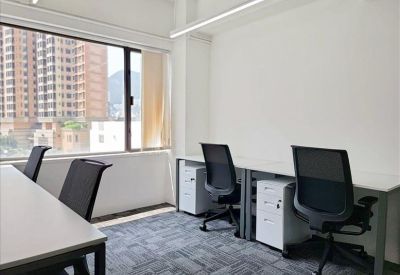 Private office with two desks and a large window showing city buildings.