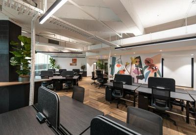 Open-plan workspace featuring dark wood desks and vibrant floral wall art.