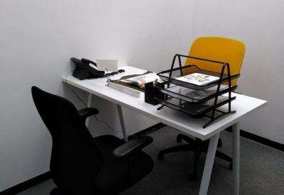Private office workspace with a white desk, yellow chair, and document trays.