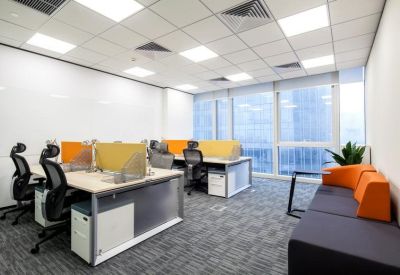 Bright open-plan workspace with multiple desks and ergonomic chairs featuring orange accents.
