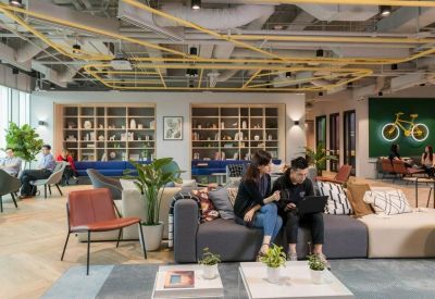 Vibrant communal lounge with diverse seating, plants, and a bicycle mural on a green wall.