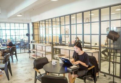 Coworking space with wooden floors, black tables, and glass partitioned walls.