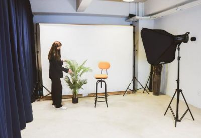 Photography studio setup with a white backdrop, light, and orange stool.