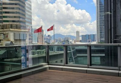 Outdoor terrace with wooden flooring and views of surrounding skyscrapers under a blue sky.