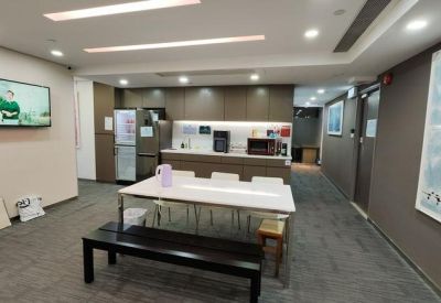 Shared kitchen and break area with a dining table, appliances, and a wall-mounted TV.