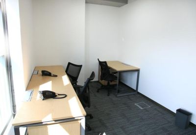 Compact private office with two light wood desks and black ergonomic chairs.
