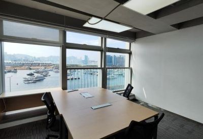 Bright conference room with a wooden table, ergonomic seating, and views of a harbour.