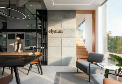 Bright reception lounge area with a grey armchair, wooden accents, and natural light.