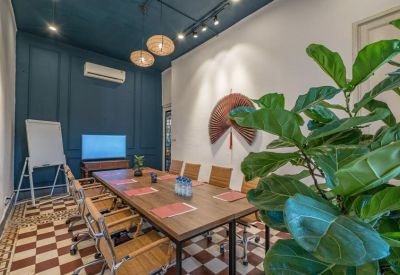 Meeting room with a long wooden table, teal feature wall, and checkered tile flooring.