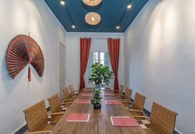 Narrow conference room with red curtains, wall-mounted fan art, and a dark blue ceiling.