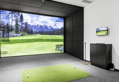 High-tech golf simulator room with a large screen and green hitting mat.
